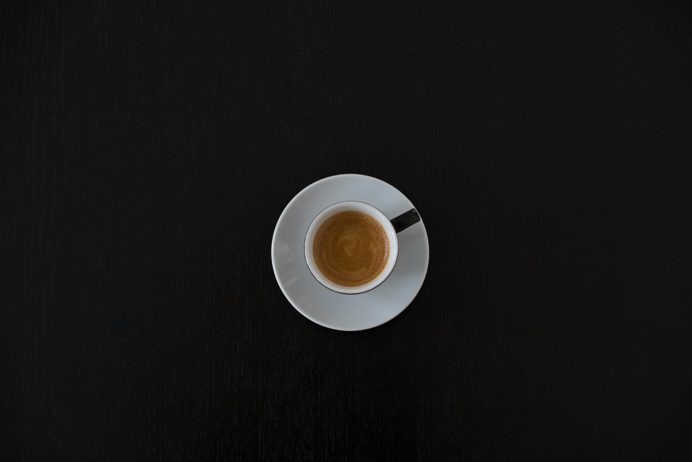 Espresso cup on a saucer against a black background